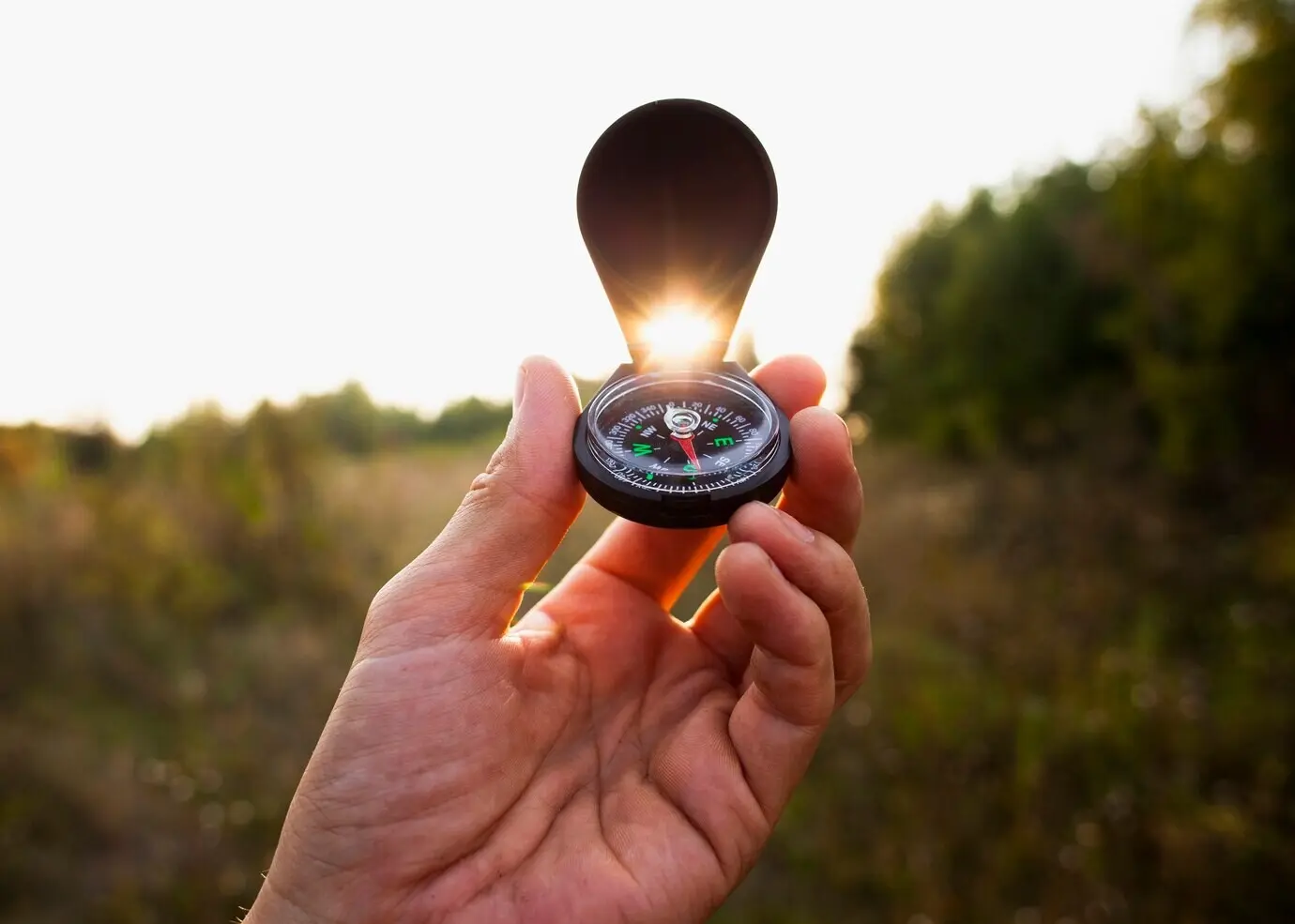 Eine Hand hält einen Kompass in der Luft.