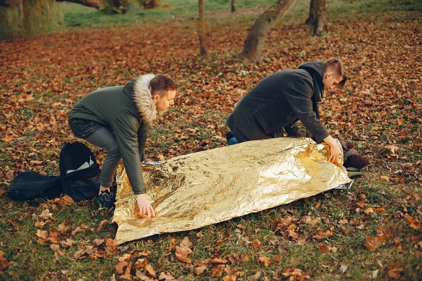 Ein afrikanisches Mädchen ist in eine warme Schutzfolie gehüllt. Jungs helfen einer Frau. Im Park wird Erste Hilfe geleistet.